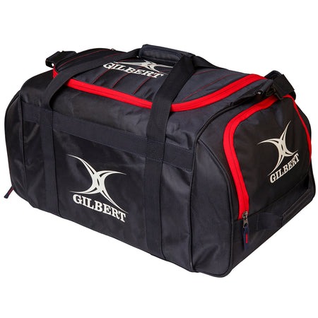 The Gilbert Performance Holdall is a black kit bag with red trim, zippered compartments, two handles, and a shoulder strap. The white Gilbert logo and name appear on the side and end of this branded rugby holdall.