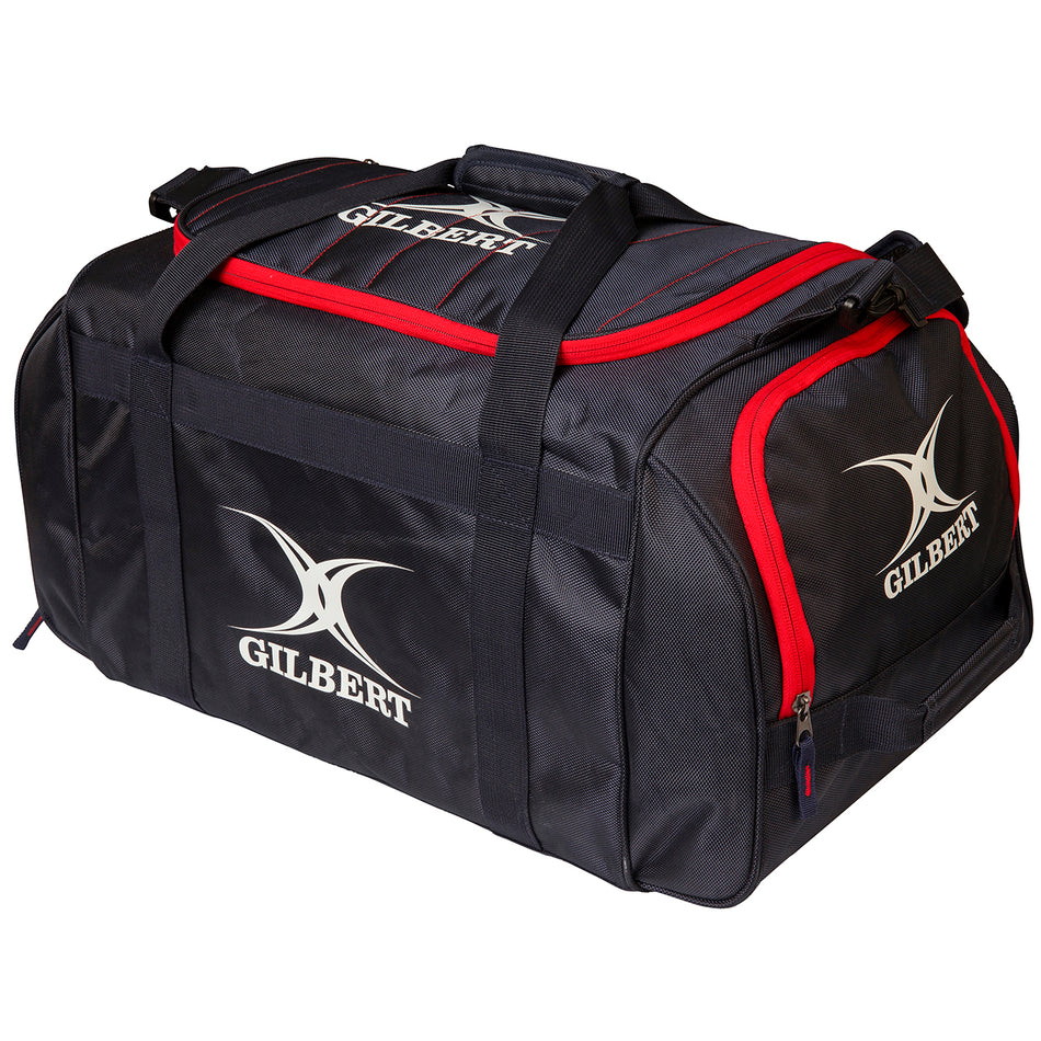 The Gilbert Performance Holdall is a black kit bag with red trim, zippered compartments, two handles, and a shoulder strap. The white Gilbert logo and name appear on the side and end of this branded rugby holdall.