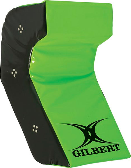The Gilbert Technique Wedge is a green and black L-shaped rugby tackle shield by Gilbert, featuring their logo on the lower front corner. This padded equipment helps improve tackling technique and player safety during contact training.