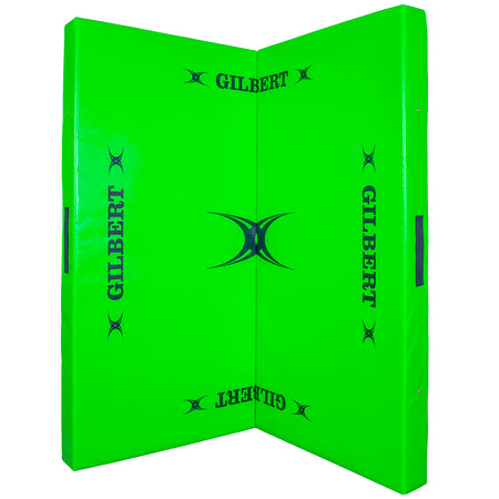 The Gilbert Tackle Mat is a bright green padded contact training mat with high-density foam, featuring GILBERT branding and black logos on both panels; shown standing open at a right angle.