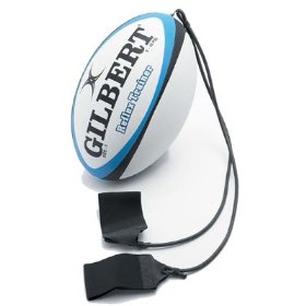 The Gilbert Reflex Trainer Rugby Ball by Gilbert is a white and blue ball with two black elastic straps and foot loops, designed for solo rugby training and to help improve passing skills.