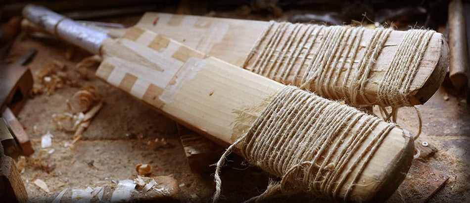 Two unfinished cricket bats with twine-wrapped handles lie amid wood shavings and tools, evoking expert repair in progress—Martin Berrill Sports’ Cricket Bat Repair (Toe, Shoulder & Edge).