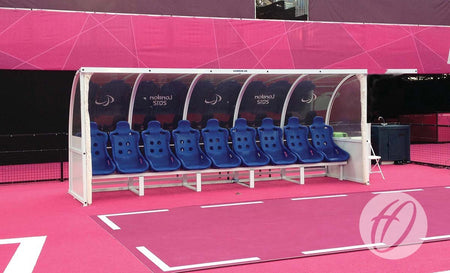 The Harrod Sport Superior Team Shelter - 4M Blue 7 Seats Fixed provides a transparent aluminium-covered bench area for teams on the sports field.