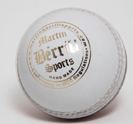 A close-up of the MBS Supreme Crown Cricket Ball (White), this hand-stitched leather ball by Martin Berrill Sports features visible stitching, branding, "Hand made" text and details about meeting MCC regulations.