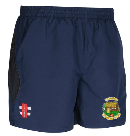 The Gray Nicolls Stanway CC Velocity Training Shorts are navy blue with an elastic waistband, black mesh side panels, and two embroidered logos: a red and white shield and a thatched building reading Stinchin Cricket Club.