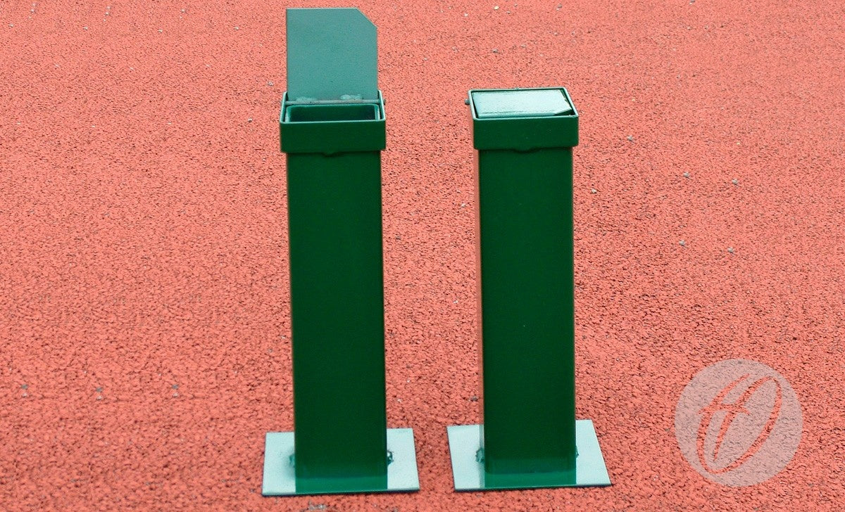 Two green metal outdoor ashtray bins stand on a textured red ground, each mounted on bases similar to Harrod Sport S8 Post Spare Sockets. One bin’s lid is open; the other is closed.