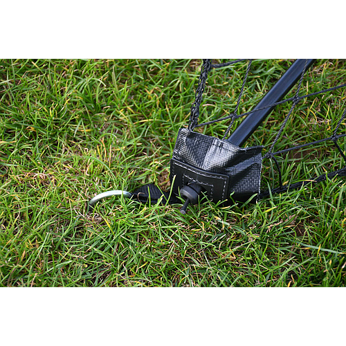 A close-up of the Precision Training Precision Quick Setup Portable Rebounder (5ft x 3ft) shows its black net, metal pole staked in grass with a fabric sleeve and ground pin, highlighting the adjustable angle for fast, easy setup.