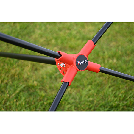 Close-up of a red plastic joint labeled Precision attaching black metal rods at an angle, with green grass behind—featured on the Precision Training Quick Setup Portable Rebounder (5ft x 3ft), designed for fast assembly and effective practice.
