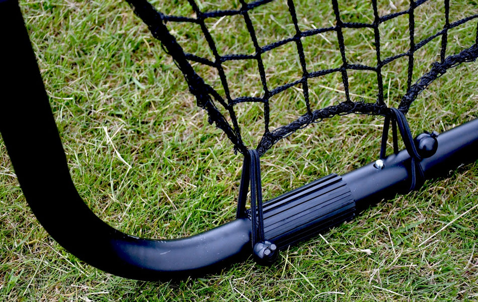 Close-up of the Precision Training Precision Pro Jumbo Rebounder on grass, highlighting its 9ft x 7ft net securely attached to the sturdy metal frame with elastic straps.