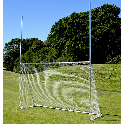 The Precision Training Precision Multi Sport Steel Goal features a zinc-coated steel frame, a rectangular soccer net, and tall rugby/football poles, set on grass with trees and a blue sky in the background.