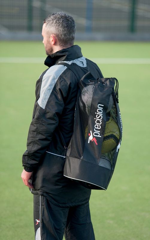 A man carrying a Precision Training Precision Tubular 3 Ball Match Bag, featuring a sturdy shoulder strap and made from durable nylon mesh.
