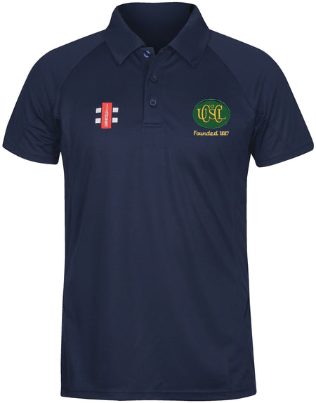The Gray Nicolls Upton St Leonards CC Matrix V2 Junior Polo Shirt is navy blue with a collar, features a red and white logo on the right chest, and a green and yellow USL CC crest with “USC Founded 1867” on the left chest.