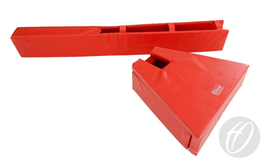 Two red Harrod Sport Competition Volleyball Post & Base Protectors: one is rectangular, the other a triangular wedge with cut-out handles. Both have smooth vinyl covers and a circular white logo in the bottom right corner.
