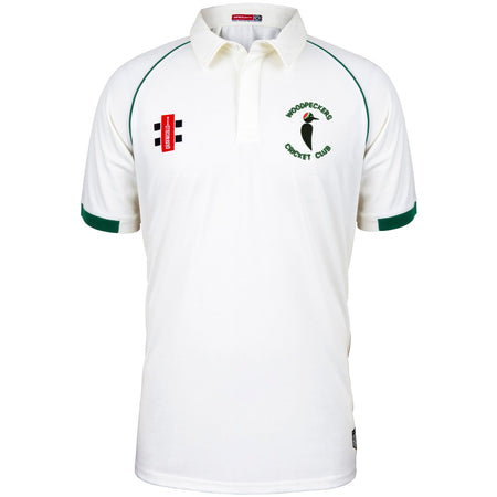 The Woodpeckers CC Matrix V2 Short Sleeve Match Shirt by Martin Berrill Sports is a white cricket shirt with green trim, moisture-wicking fabric, and embroidered logos for Woodpeckers Cricket Club and sponsors on the chest.