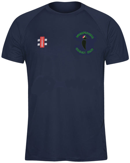 The Gray Nicolls Woodpeckers CC Matrix V2 T-Shirt is a navy short-sleeve cricket training top with a red and white club logo on the right chest, a green and black bird crest on the left, and moisture-wicking fabric for comfort.