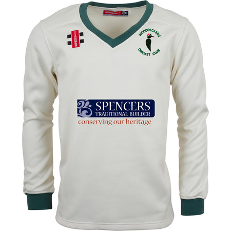 The Gray Nicolls Woodpeckers CC Pro Performance Sweater is a cream long-sleeve top with sport-specific fabric, green trim on collar and cuffs, the Woodpeckers Cricket Club logo, and sponsor logos on the chest.