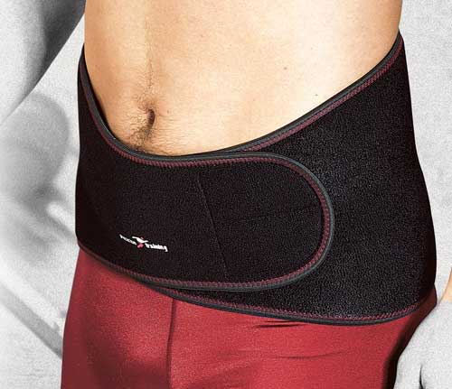 A person wears the Precision Training Precision Neoprene Back Support Universal with red trim over red shorts. The belt wraps tightly around the waist, fastening in front to provide relief and stability for back pain or lumbago.
