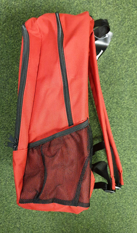 The PenCarrie Checkers Gymnastics Rucksack, in red with black zippers, mesh side pocket, padded back panel, visible shoulder straps and handle, is placed on a green textured surface.