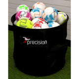 The Precision Training Ball Bin - POS/On Field, in black, is filled with vibrant soccer balls—white, pink, blue, green, orange, and yellow—and sits on a green floor against a wall with white paneling.