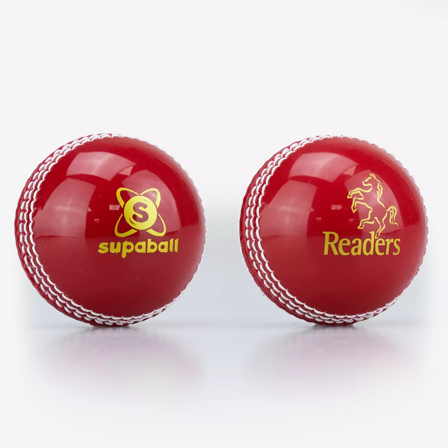 Two shiny red Readers Supaball cricket balls with white stitching and yellow horse logos are displayed side by side.