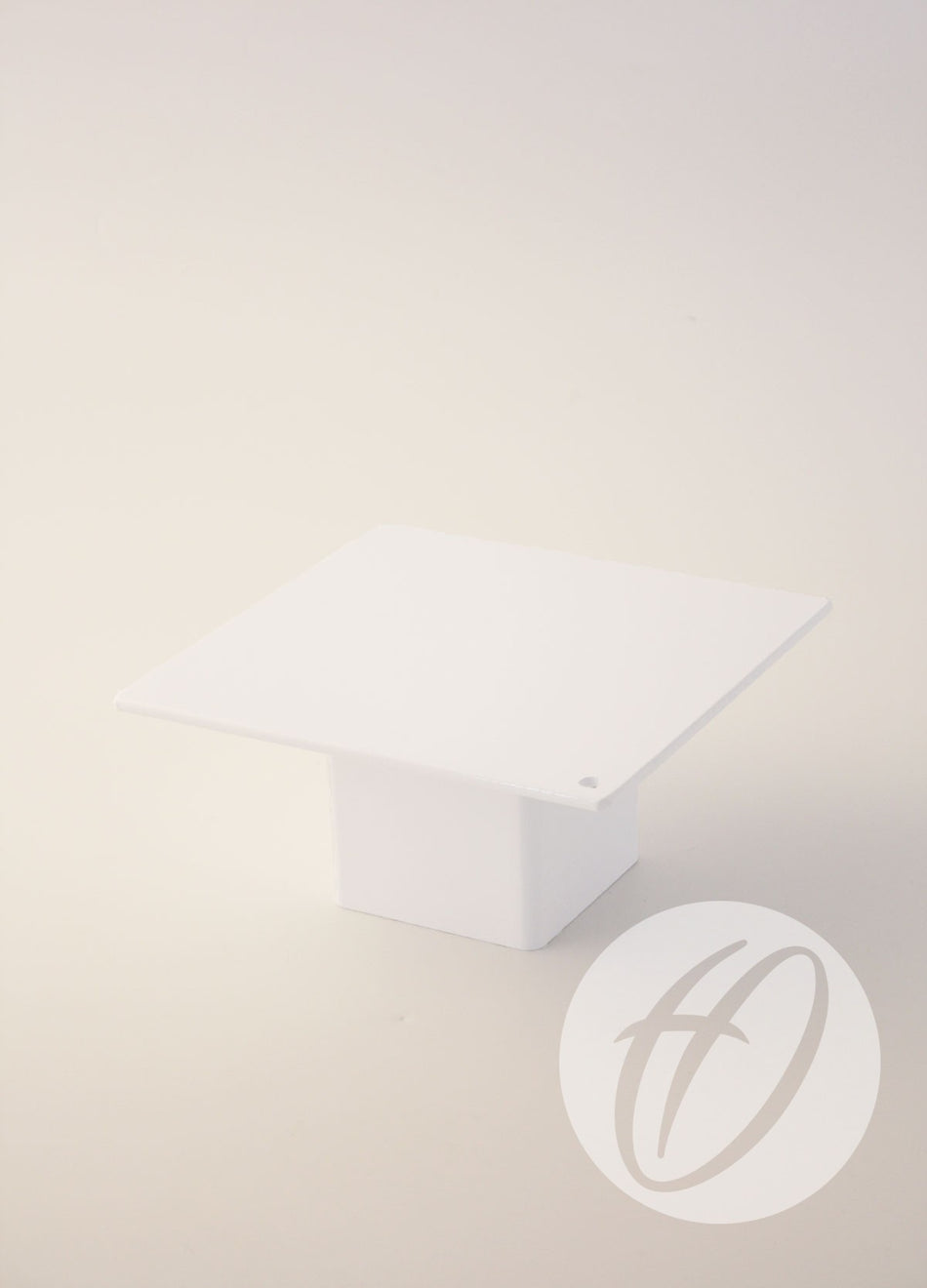 A minimalist white square pedestal with a flat top and rectangular base, set against a plain light background, displays Harrod Sport's Millennium Rugby Drop-In Socket Lids. A circular watermark with a stylized h appears in the lower right corner.