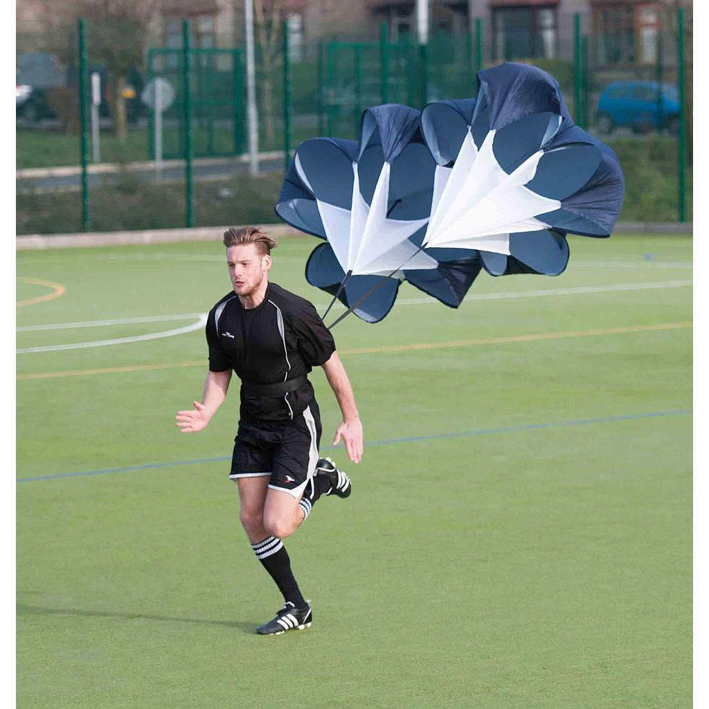 A man in athletic wear runs on a field with the Precision Training Precision Pro Dual Speed Chute attached to his waist, using it for resistance training to boost speed and strength.