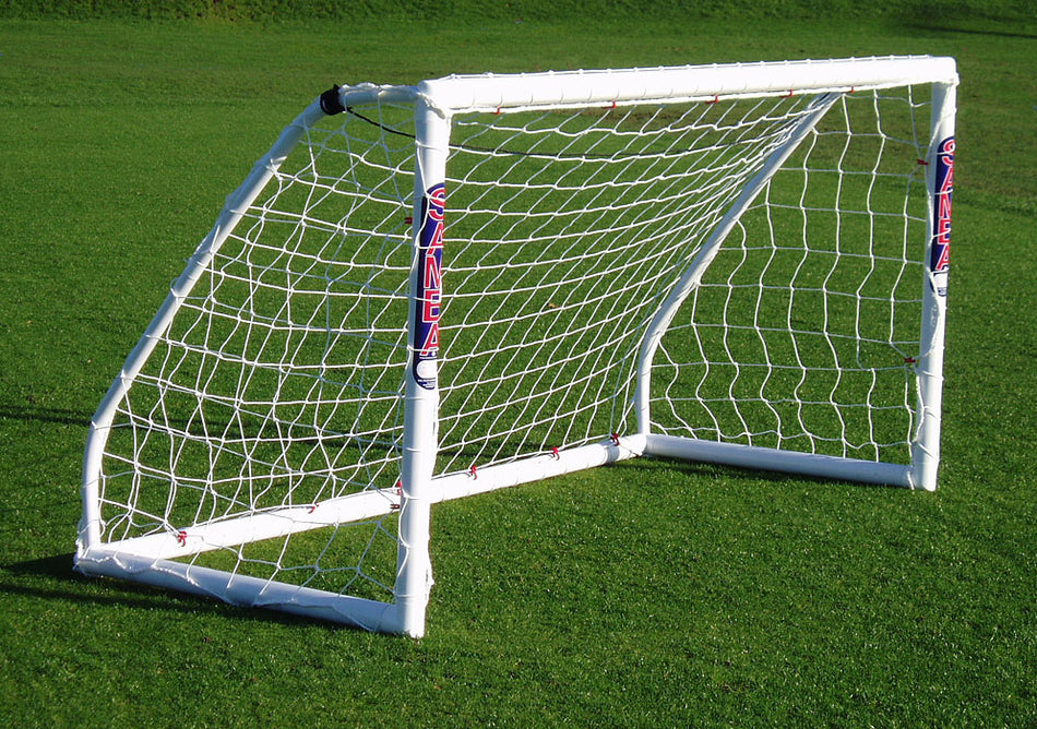A Samba Sports Samba Match Goal 8 x 4 with netting stands on bright green grass. Marked with GINEL in red and blue, this easy-to-assemble white football goal casts a shadow across the field.