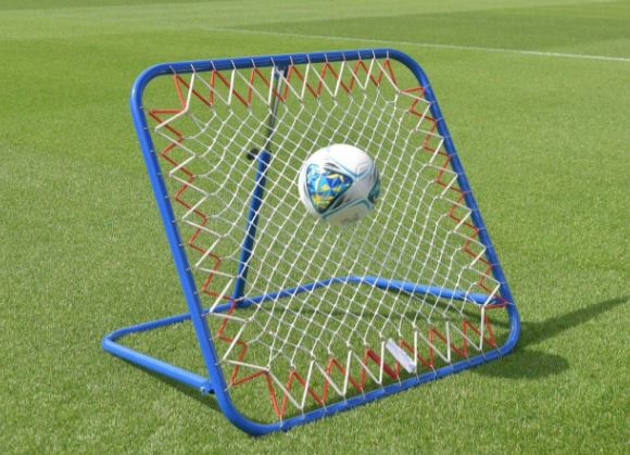 A soccer ball bounces off a Samba Sports Pro Rebounder, ideal for first touch drills, on a grassy field.