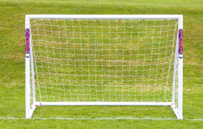 A 7'10 x 5'3 Mini Handball Goal by Samba Sports, featuring a shatterproof uPVC frame and net, stands on a green field. The white posts display SAMBA SPORTS branding in red and blue, with visible horizontal lines in the background.