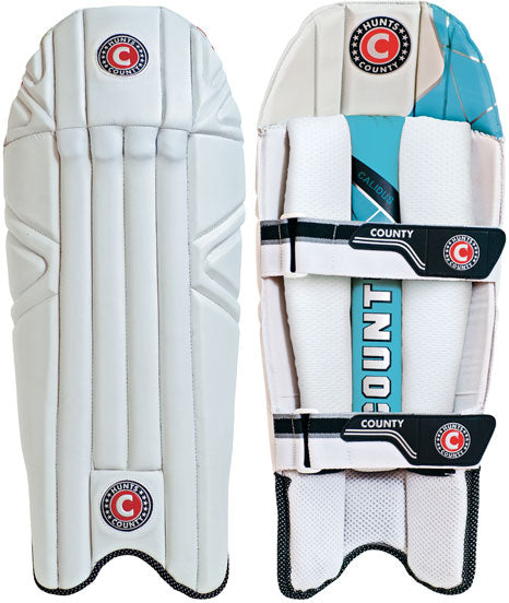 Two white Hunts County Calidus Wicket Keeping Pads are displayed: the front view on the left with stitched panels and a circular logo, and the back on the right showing blue accents, adjustable straps, and a COUNTY logo.