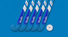 Five aqua/royal Uwin TS-X Hockey Sticks from Uwin are arranged diagonally on a blue textured surface, with a white field hockey ball labeled Vwin positioned at the lower right of the sticks.