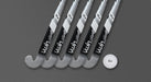 Five metallic silver and black Uwin TS-X hockey sticks from Uwin are lined up diagonally on a gray textured surface. A white field hockey ball, also bearing the Uwin logo, sits to the right of the sticks.