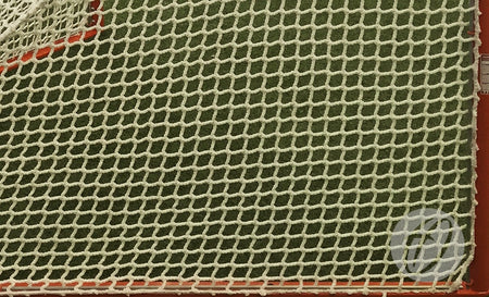 Close-up of a Harrod Sport Competition Lacrosse Nets 5MM in white, featuring heavy-duty knotless netting securely attached to a red metal frame, with green artificial turf visible in the background.