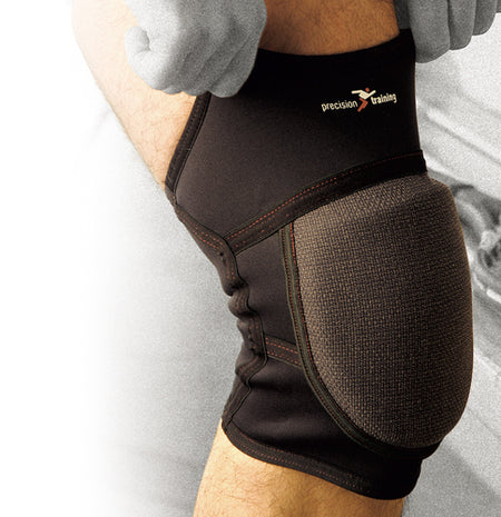 A person wears the Precision Training Precision Neoprene Padded Knee Support on their bent knee, with a gloved hand resting on their thigh, to help prevent knee injuries.