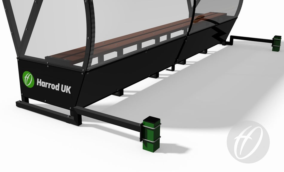 A close-up of a black and transparent Harrod Sport Panoramic Team Shelter Anchor with a wooden bench inside, set on a white surface. The shelter features sturdy support posts and green end weights.