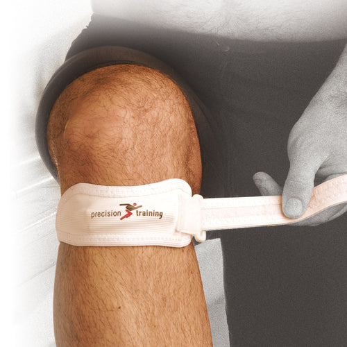 A person wearing dark shorts adjusts a white Precision Patella Strap by Precision Training below their knee. The strap provides light compression to support or relieve conditions like Patella Tendonitis.