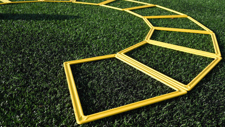 Precision Training’s Precision Poly Grid System (set of 10) features yellow plastic agility grids arranged in a zigzag pattern on green artificial grass, ideal for agility training and enhancing footwork skills.