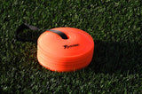 A stack of bright orange Precision Pro Near Flat Markers by Precision Training with a black handle rests on green artificial grass. The top cone features the brand logo, making this set of 40 ideal for soccer training drills.