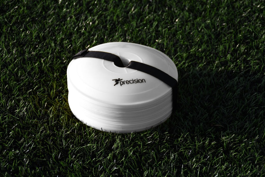 A stack of Precision Pro Near Flat Markers (set of 40) by Precision Training, secured with a black strap, rests on green artificial grass. The top white marker features the Precision Training logo and branding.