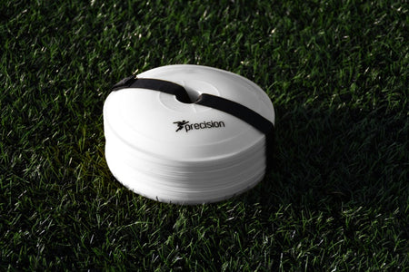 A stack of Precision Pro Near Flat Markers (set of 40) by Precision Training, secured with a black strap, rests on green artificial grass. The top white marker features the Precision Training logo and branding.