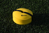 A stack of Precision Training Pro Near Flat Markers (Set of 40) with a black strap rests on artificial grass. These yellow, low-profile soccer markers are perfect for training sessions.