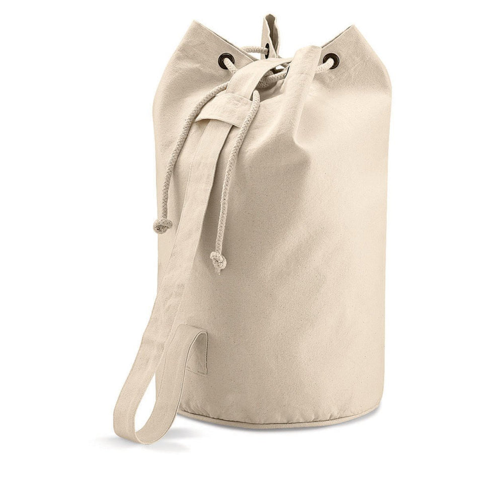 The Quadra Duffle Style Ball Sack is a durable beige canvas bag with drawstring closure, metal grommets, and a single shoulder strap—ideal for carrying balls. It stands upright against a white background.