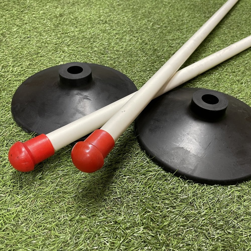 Four Sure Shot Wooden Rounders Posts with red safety caps are shown crossed on artificial grass, alongside two heavy-duty black rubber bases. The equipment is branded Sure Shot and is ideal for sports or training use.