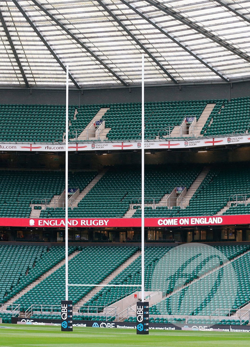 An empty rugby stadium features green seats, Harrod Sport Millennium Rugby Posts - 17M Hinged at the center, a digital sign reading ENGLAND RUGBY COME ON ENGLAND, and England flags draped on the upper seats.