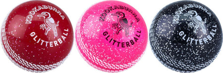 Three Kookaburra Glitter balls—red, pink, and black—are displayed side by side, each featuring white speckles and the Kookaburra logo on a soft plastic surface.