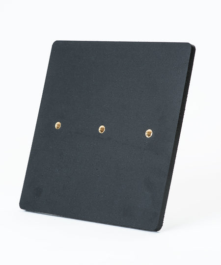 The Fusion Multi-Stump All Weather Base by Fusion is a square black textured panel with three evenly spaced brass-colored holes in a horizontal row, shown on a plain white background. It’s ideal for hard wicket cricket and built for all-weather use.