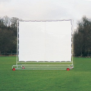 The Martin Berrill Sports Standard Sight Screen - Galvanized features a large rectangular frame and red wheels, standing on grass with trees and clouds in the background.