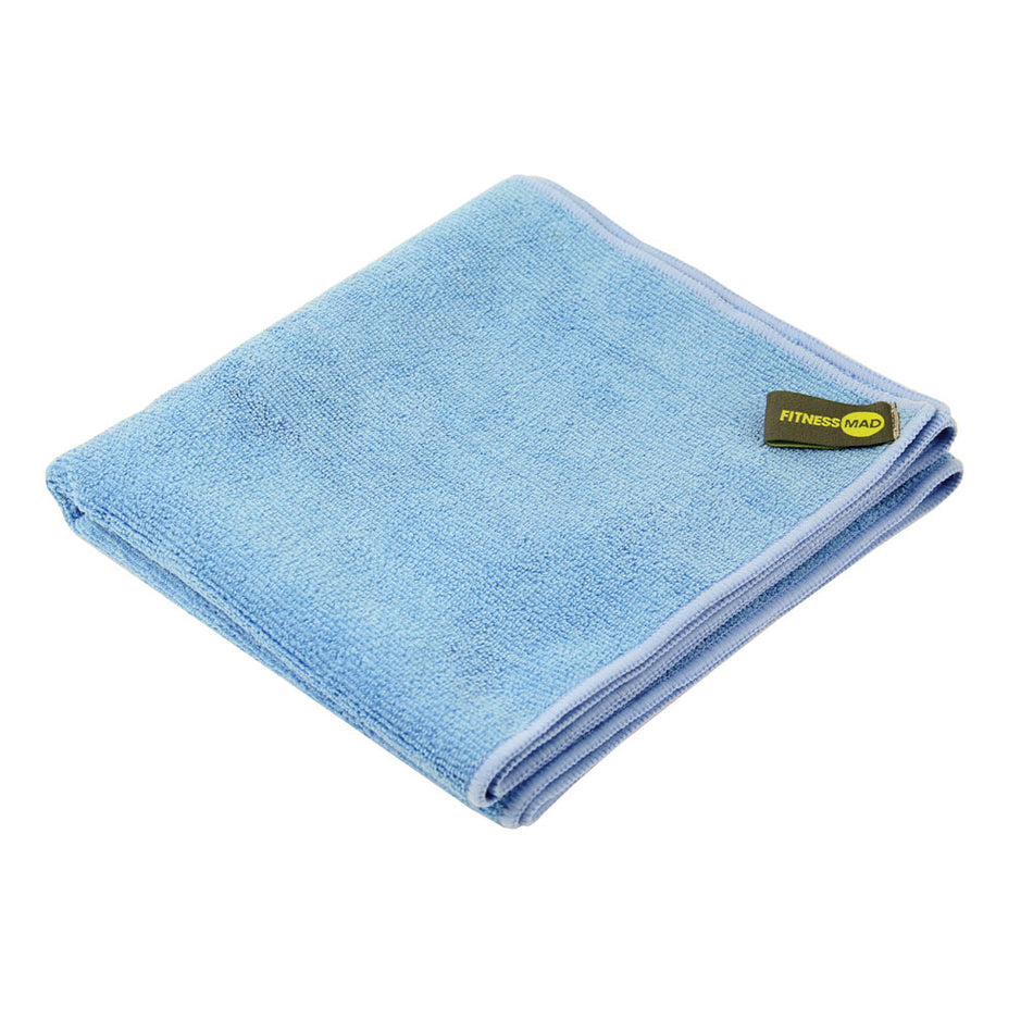 The Fitness Mad Gym Towel is a folded light blue microfibre towel with a small Fitness Mad tag in yellow and black on one corner, shown against a white background.