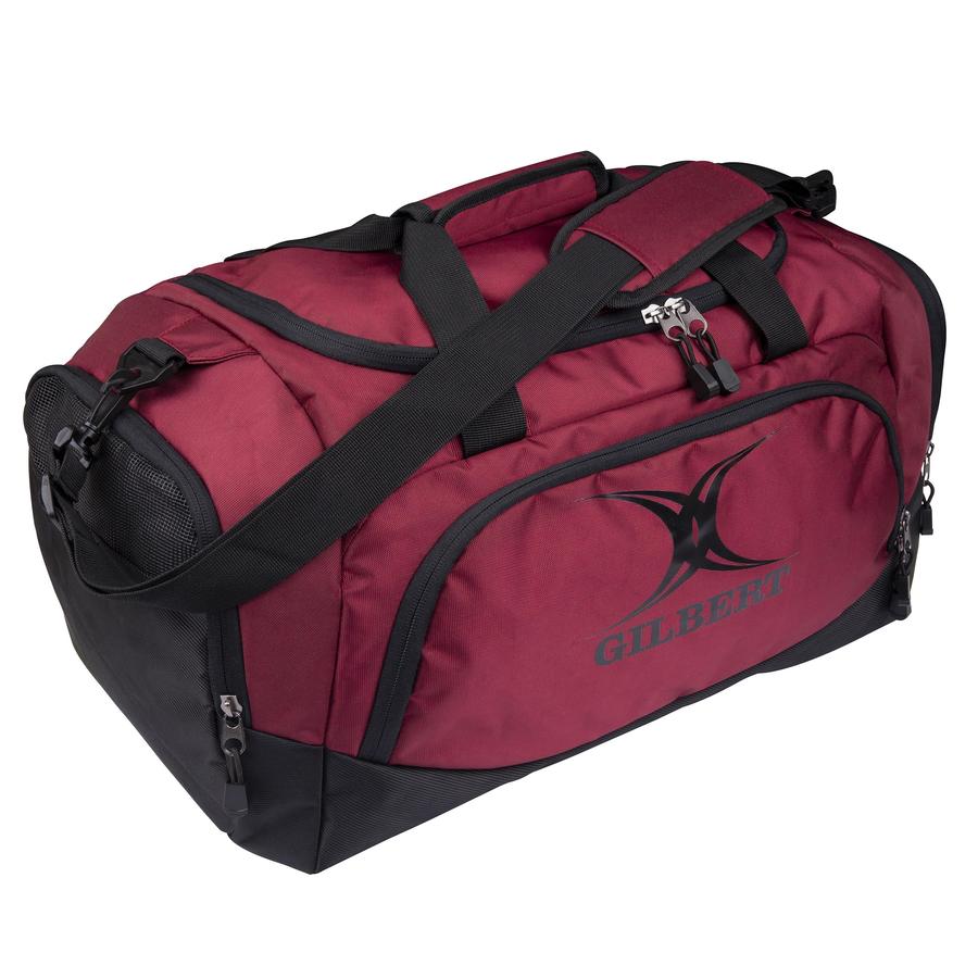 The Gilbert V3 Club Player Holdall is a maroon sports bag with multiple zippered compartments, black straps and handles, a padded shoulder strap for comfort, and features the Gilbert logo on the side pocket.