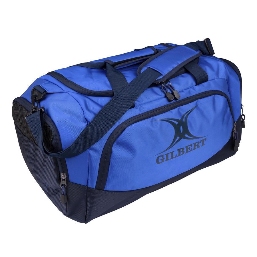 The Gilbert V3 Club Player Holdall is a navy/royal sports kit bag with shoulder and hand straps, a side pocket featuring the Gilbert logo, and multiple zippered compartments for organized storage.